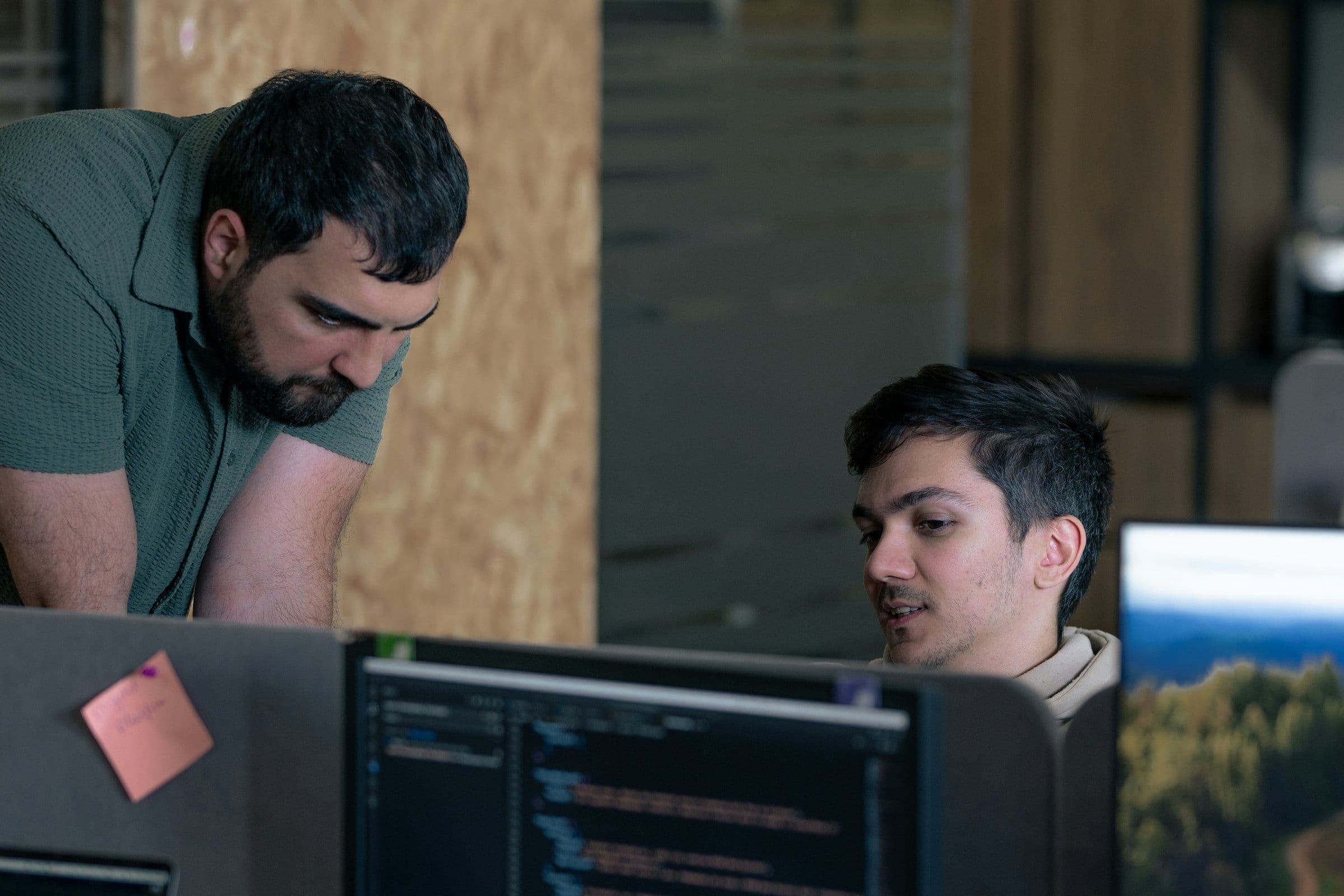 Two developers reviewing code together on a monitor before a change goes live